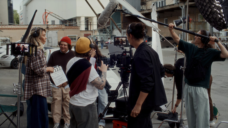Cinema camera, boom operator and crew on an exterior production set.